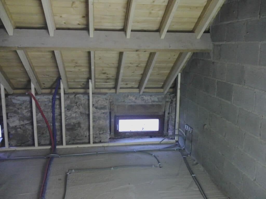 Combles d'une maison en cours d'isolation : chevrons neufs, mousse projetée sur les murs, relevés lors d'un audit logement